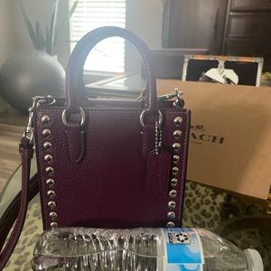 Coach mini studded top grain leather plum color and silver. Fits an iPhone 7